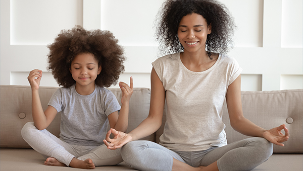 Mother and Daughter Doing Yoga Together on Couch