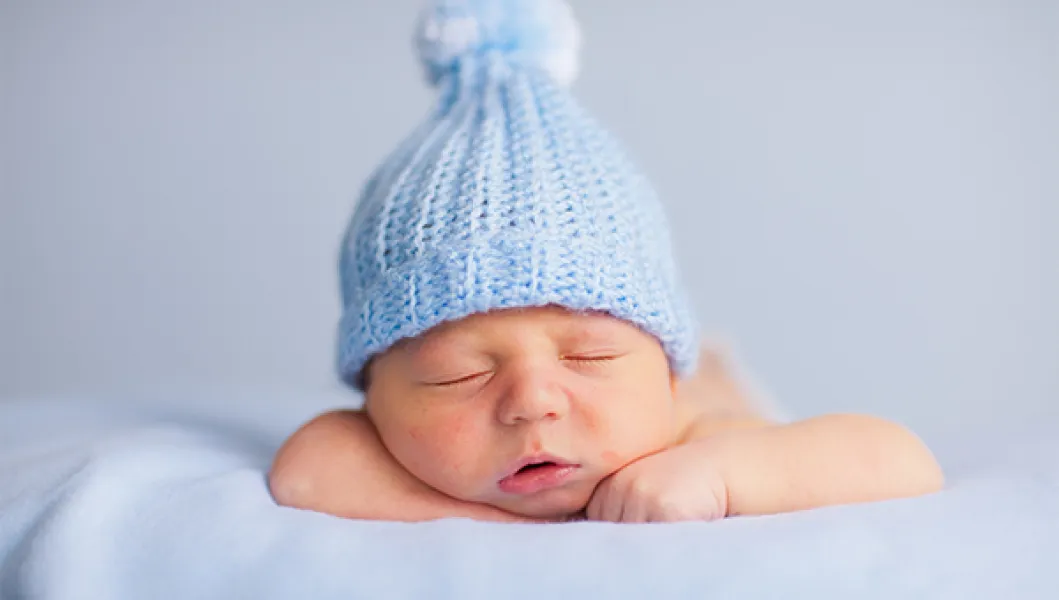 Baby with blue hat on and blue background. Baby is sleeping peacefully