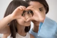 Mom and daughter making heart hands.