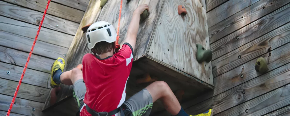 Teen boy belayed on a climbing wall