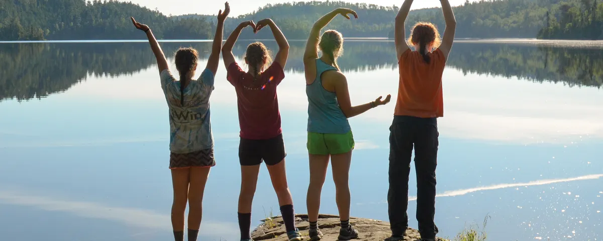 Four teens overlooking lake in YMCA pose