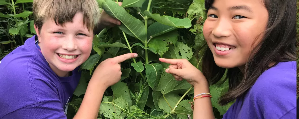 Two youth pointing at a chrysalis