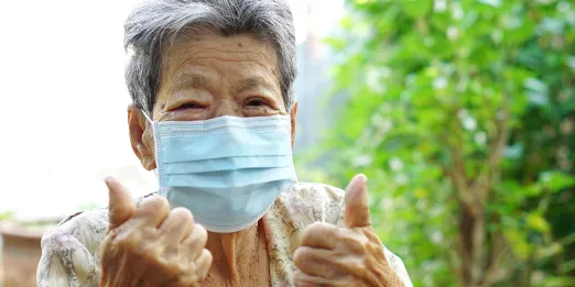 Older woman wearing mask and giving 'thumbs up'